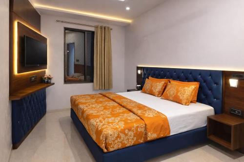 a bedroom with a large bed with orange pillows and a television at The Shree Ganesh Hotel in Khātu