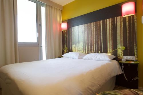 a bedroom with a large white bed and a window at ibis styles Dax Centre in Dax