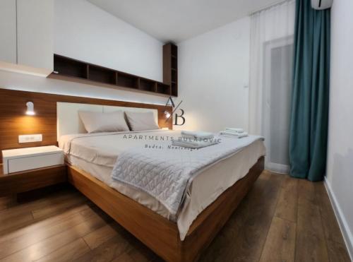 a bedroom with a large bed with a wooden headboard at Apartments Bulatovic in Budva