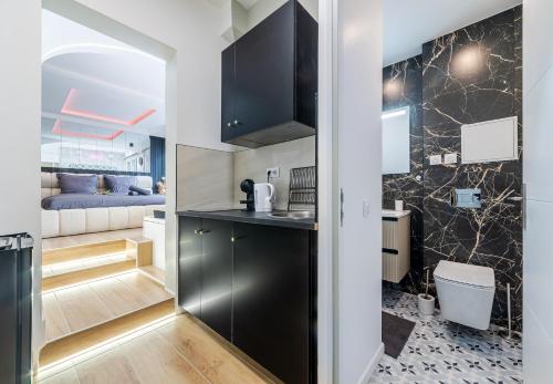 a kitchen with black cabinets and a living room at Escapade à deux à 10mn de Paris in Gentilly