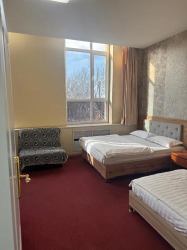 a hotel room with two beds and a window at Zolotoi Drakon Hotel in Almaty