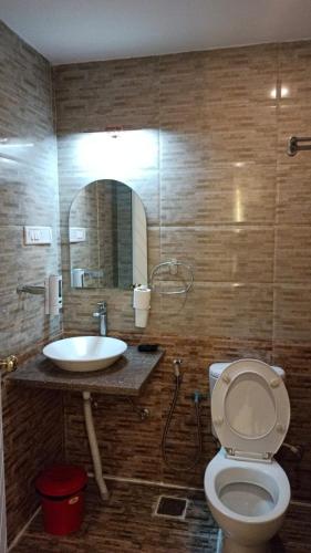 a bathroom with a sink and a toilet and a mirror at Feel Goa at Poolview 2BHK Luxury Apartment in Arpora