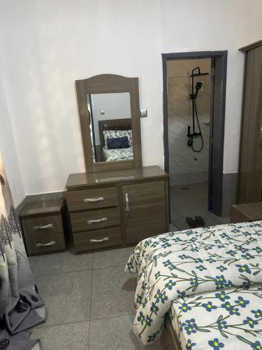 una camera da letto con una cassettiera con uno specchio e un letto di Sylla hourse's a Conakry