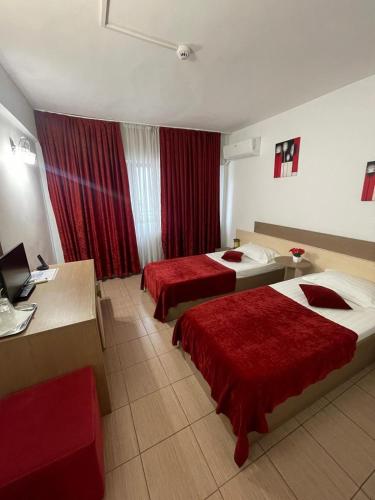 a hotel room with two beds with red sheets at Hotel Ciucas in Vălenii de Munte
