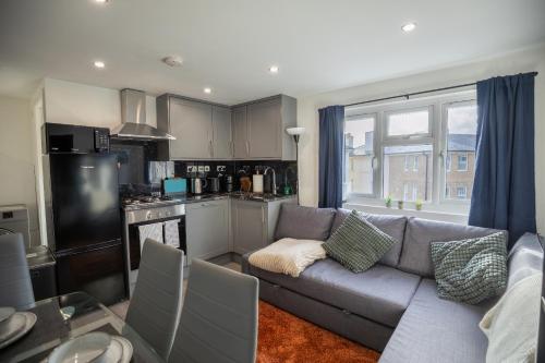 a living room with a couch and a kitchen at Cozy 2 Bed Flat in Town Centre in Royal Tunbridge Wells