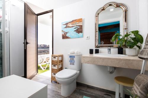 a bathroom with a toilet and a sink and a mirror at Cabin in front of idyllic majanicho beach in Majanicho