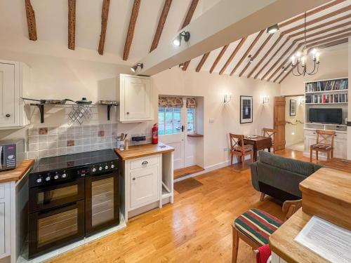 a kitchen and living room with white cabinets and a table at Leacon Hall Lodge in Orlestone