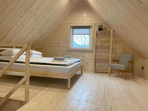 a bedroom with a bed and a chair in a attic at Astroturystyka Izeria in Leśna
