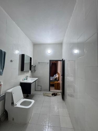a white bathroom with a toilet and a sink at Résidence NDAR CHAMBRES in Saint-Louis