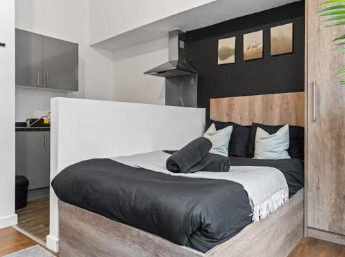 a bedroom with a large bed with black sheets and pillows at Cheerful Central Studio - 2 in Leicester