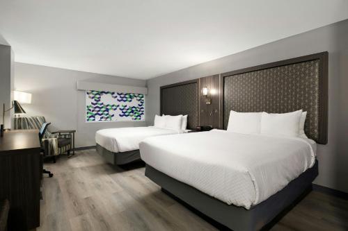 a hotel room with two beds and a desk at Verta Hotel McAllen in McAllen