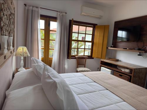 a bedroom with a bed and a desk and a window at Pousada Neuza Barbosa in Tiradentes