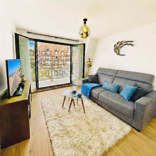 a living room with a couch and a television at Refuge Chaleureux et Lumineux, Wifi, Balcon, Parking au coeur de Deauville in Deauville