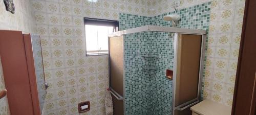 a bathroom with a shower with a toilet and green tiles at Habitaflex Casa No Centro de Urupês in Urupês