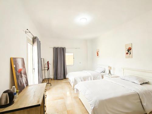 two beds in a bedroom with white walls at Villa131 Hotel in Cairo