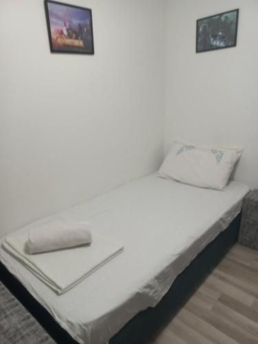 a white bed with two pictures on the wall at The Little Green House in Petrovec