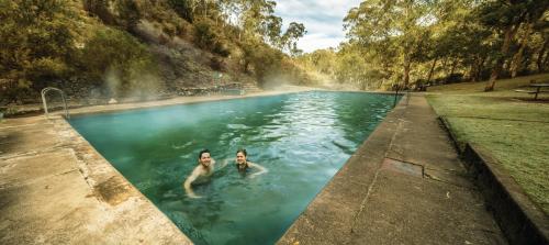 two people swimming in a swimming pool at Yarrangobilly Caves House in Yarrangobilly