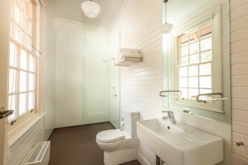 Baño blanco con aseo y lavamanos en Yarrangobilly Caves House en Yarrangobilly