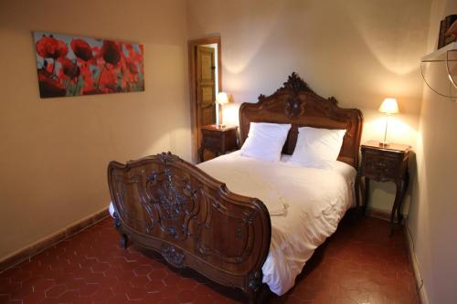 - une chambre dotée d'un lit en bois avec des draps et des oreillers blancs dans l'établissement Vacances chez l'antiquaire 15 personnes 10 chambres, à Saint-Césaire-de-Gauzignan