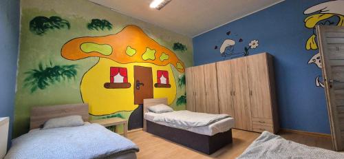 a room with two beds and a mural of a house at turistická ubytovňa LIENKA in Holíč