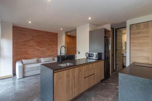 a kitchen with a counter and a couch in a room at Loft Urbano con Sala, AC y Vistas, Col Americana 603 in Guadalajara