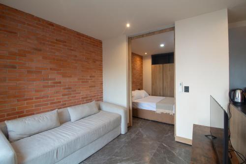 a living room with a couch and a brick wall at Loft Urbano con Sala, AC y Vistas, Col Americana 603 in Guadalajara