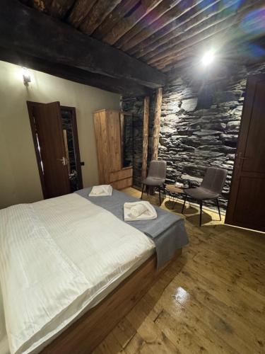 a bedroom with a bed and a stone wall at Firefly in Shatili