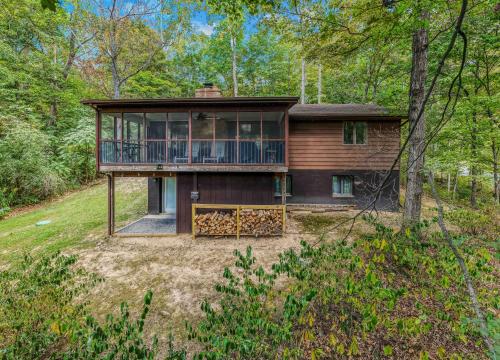 a house in the woods with a wrap around porch at Chesnutt Cabin - Riverfront, Fire Pit, Game Room, Wifi, Screen Porch, View, King Bed in Morton Grove