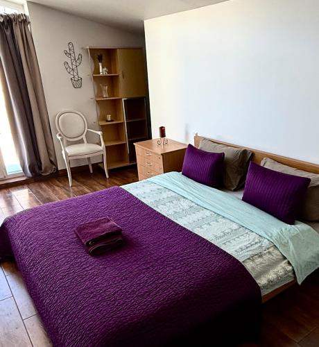 a bedroom with a large purple bed with a chair at CENTRO House in Alytus