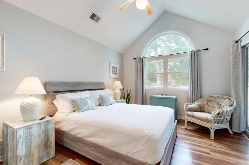 a bedroom with a bed and a chair and a window at SB25A Clubhouse Villa 2BR in Sunset Beach