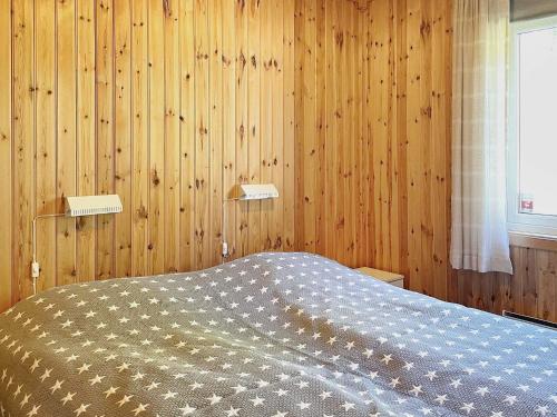 a bedroom with a bed with wooden walls and a window at 4 person holiday home in BENGTSFORS in Bengtsfors