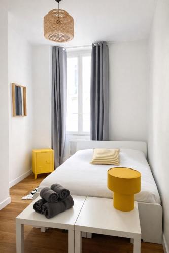 a bedroom with a white bed and a yellow stool at Appartement Marseille au cœur du panier in Marseille