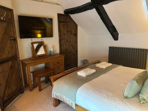 a bedroom with a bed and a dresser and a television at Priory Weavers Cottage in Burford