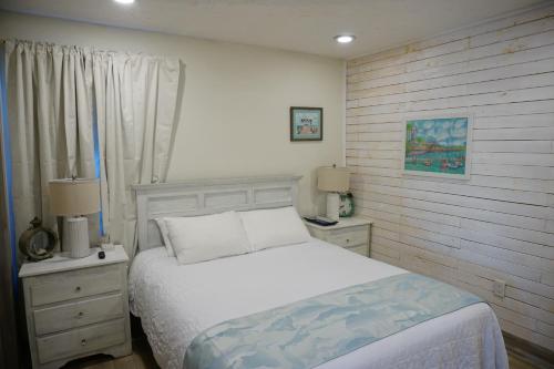 a bedroom with a white bed and two night stands at Anna Maria Island Tree House Pet Friendly! in Bradenton Beach