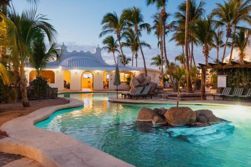 a swimming pool with palm trees and a building at Hotel & Suites El Moro in La Paz