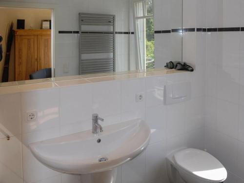 a white bathroom with a sink and a toilet at Burg Roland Wohnung 04 in Dierhagen