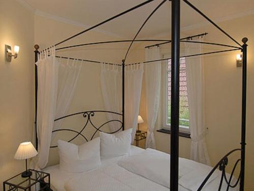 a bedroom with a black canopy bed with white pillows at Burg Roland Wohnung 04 in Dierhagen