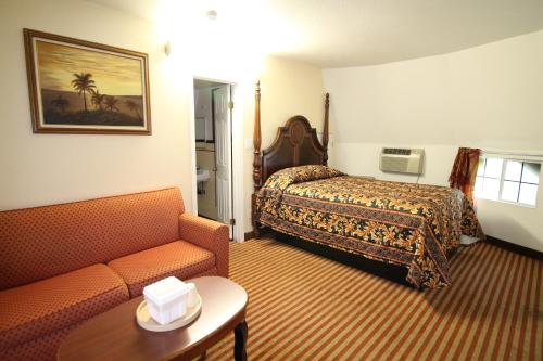 a hotel room with a bed, couch, chair and table at Wigwam Motel in San Bernardino