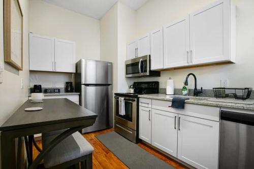 a kitchen with white cabinets and a stainless steel refrigerator at Victorian Cozy Retreat Steps to Cleveland Clinic in Cleveland
