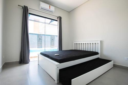 a bed in a room with a large window at Casa grande alto padrão á 100 metros do mar in Guaratuba
