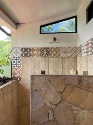 a bathroom with a tiled wall with a window at Hotel Pura Natura Beachfront Tortuguero in Tortuguero