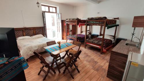 a bedroom with two bunk beds and a table and chairs at Hostal Distrito in Sucre