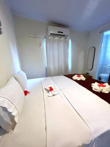a room with a large white bed with red flowers on it at Pousada do Trinta in Fernando de Noronha