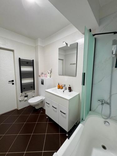 a bathroom with a sink and a toilet and a tub at Yellow Apartment in Floreşti
