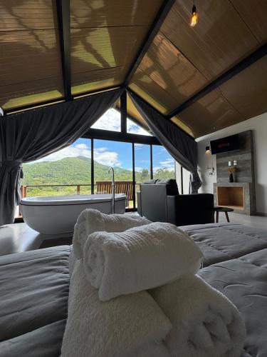 a bedroom with a bed with towels on it with a tub at Hospedagem na natureza in Garopaba