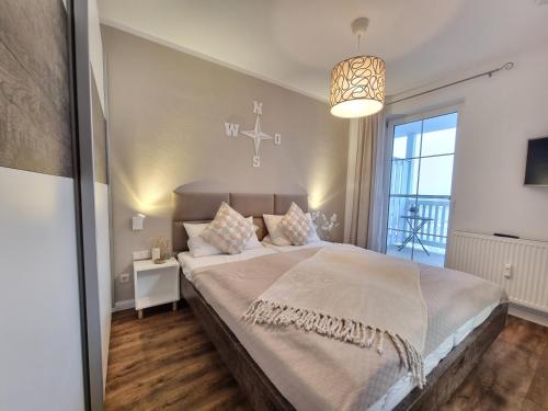 a bedroom with a large bed and a chandelier at Hafenidyll 46 - exklusiv am Yachthafen mit zwei Bädern - traumhafte Sonnenuntergänge inklusive in Karlshagen