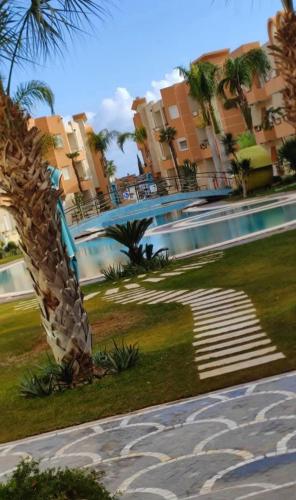 a swimming pool in a resort with palm trees and buildings at La douce in Sousse