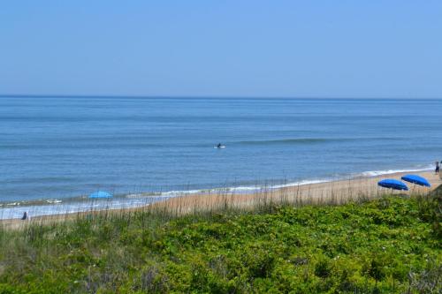 a beach with blue umbrellas and the ocean at Breakaway - Duck, Sanderling, Oceanfront, Ocean View, Pets OK, Community Pool in Duck