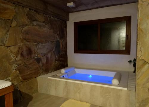 baño con bañera azul en una pared de piedra en Punta Cerezo en Cariló