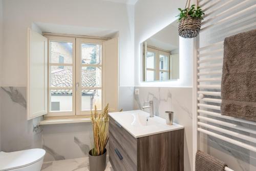 a bathroom with a sink and a toilet and a window at The Townhouse Barga in Barga